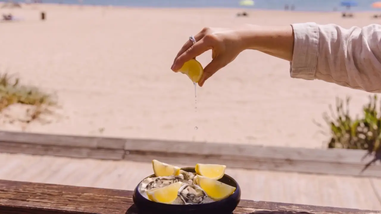 A lemon squeezed over oysters on the Portofino terrace above Praia do Ouro